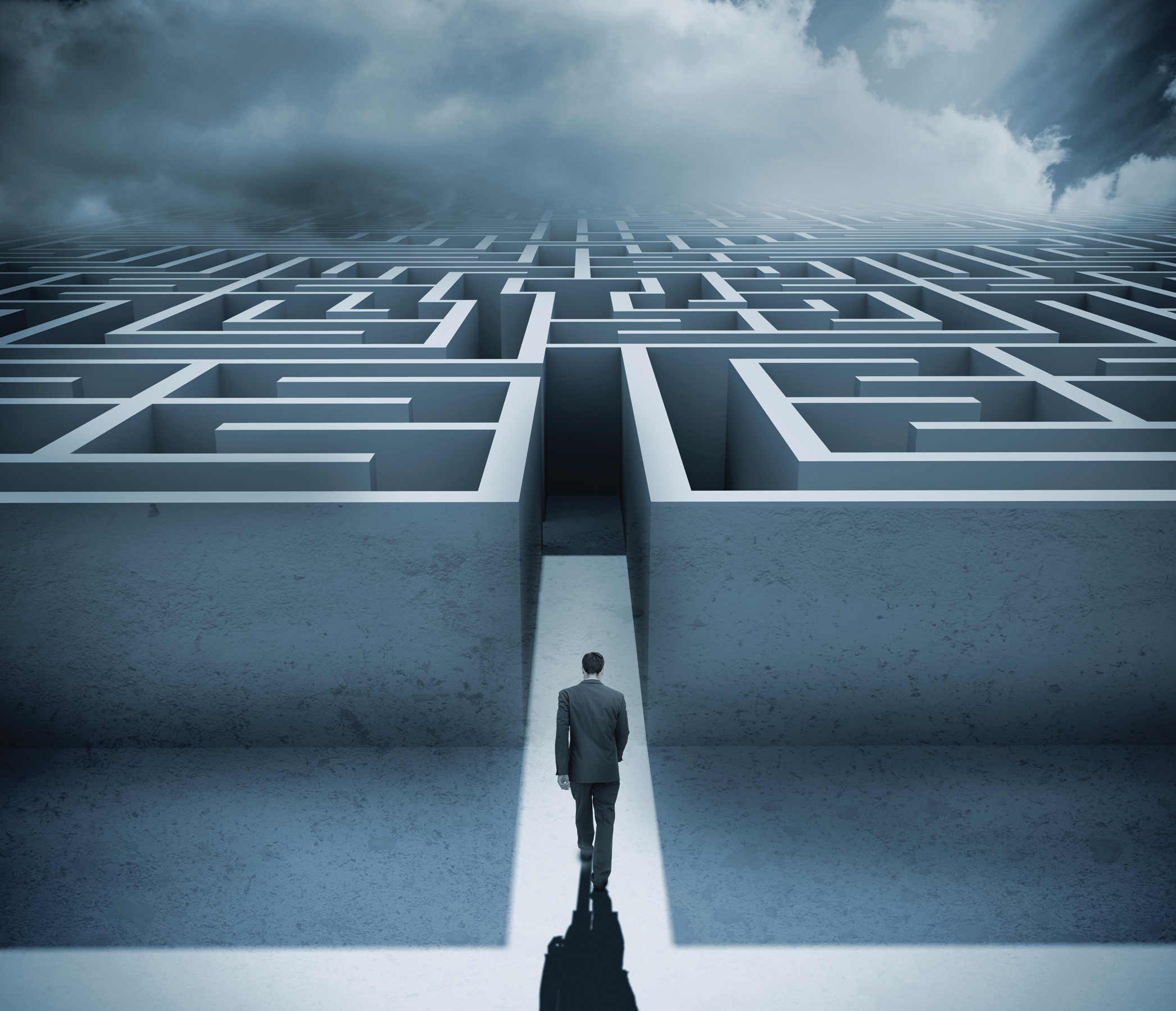 Businessman getting in a maze with dark cloudy sky on the background