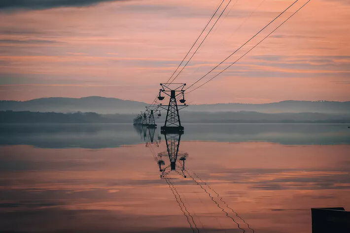 A vertical shot of an awesome view for the electrical towers in the sea and their reflection in water