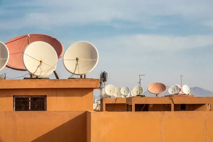 A wide angle shot of white satellite dishes on the roof of a building