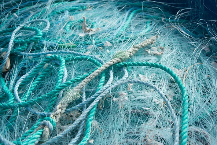 A closeup of blue ropes and fishing nets on each other under the sunlight